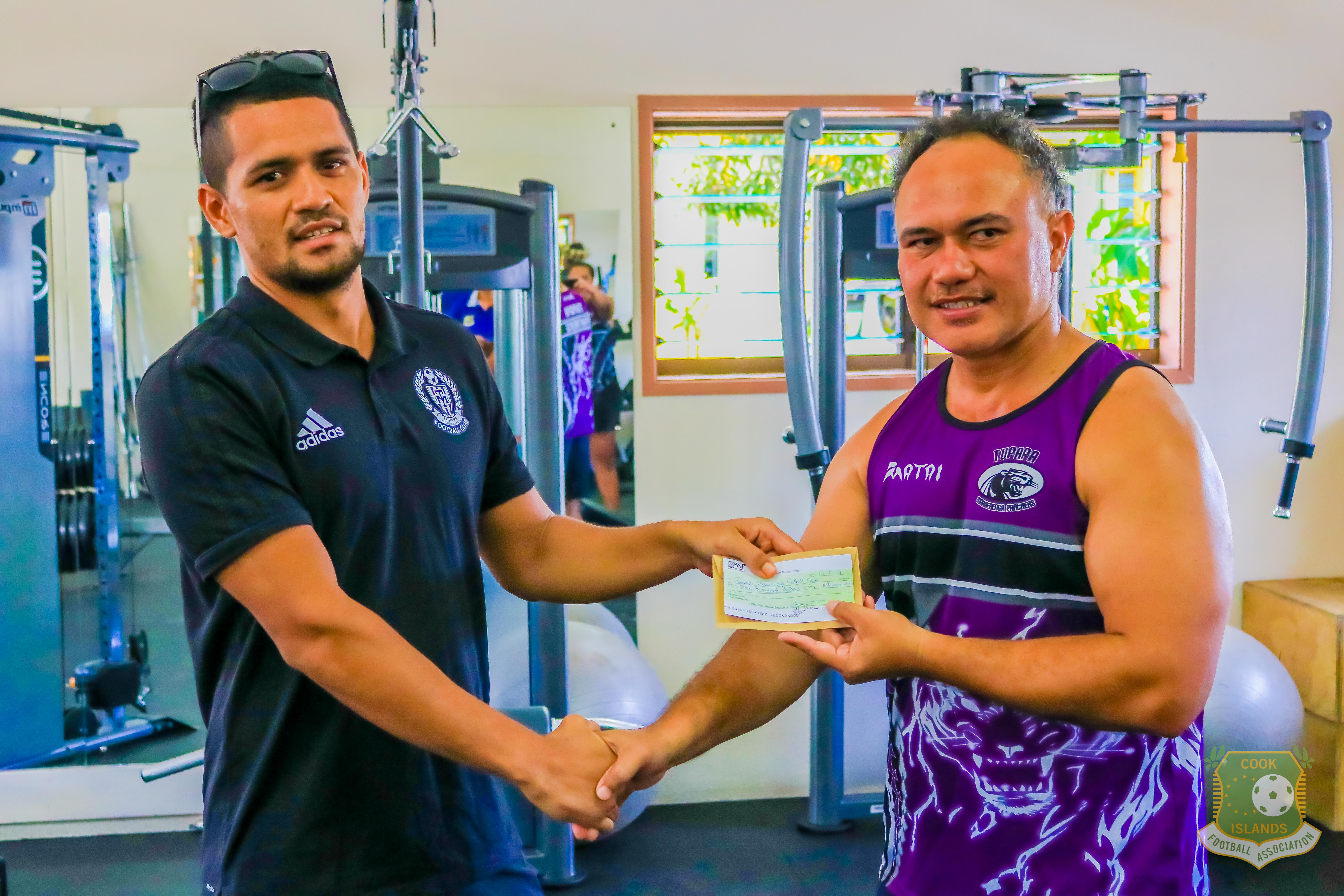 TUPAPA MARAERENGA SPORTS ASSOCIATION PRESIDENT TERE STRICKLAND HANDS OVER A DONATION TO TUPAPA MARAERENGA FC PRESIDENT, GROVER HARMON, AHEAD OF THE OFC CHAMPIONS LEAGUE 2019